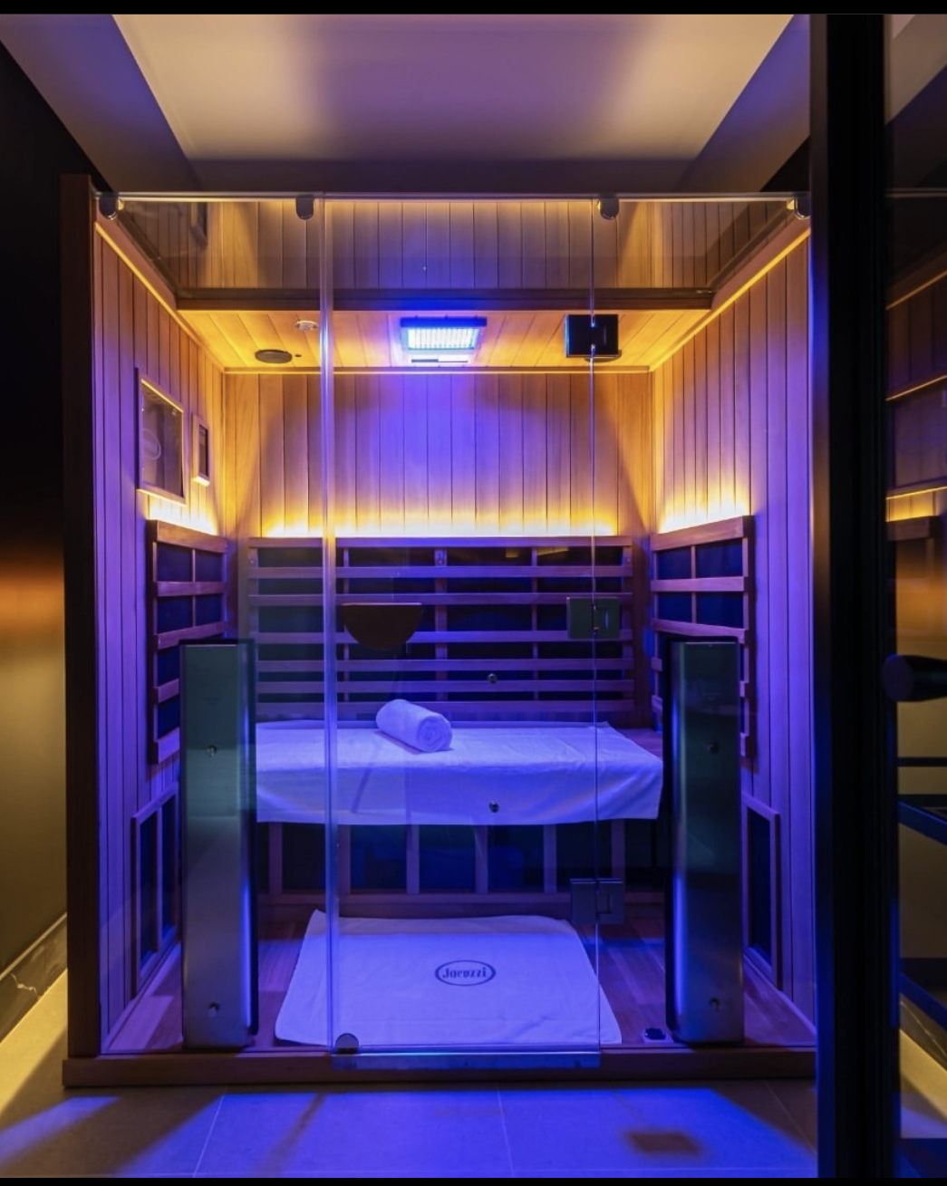 Private duo infrared sauna room with purple chromotherapy lighting and two benches