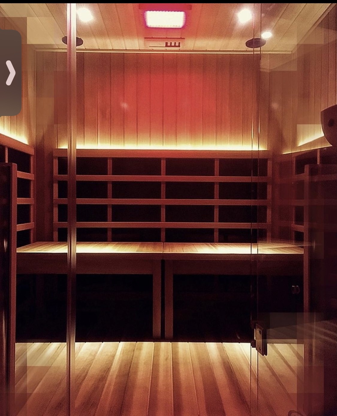Private solo infrared sauna room with warm amber lighting and cedar wood interior
