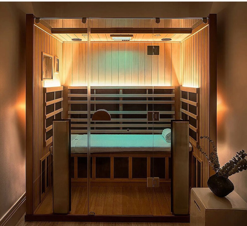 Infrared sauna with cedar wood interior and teal chromotherapy lighting at Infrared Sauna Studios